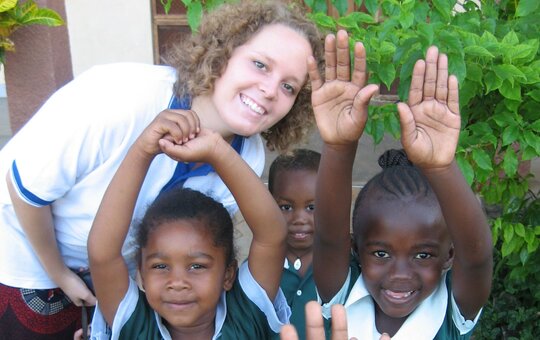 Ein Mädchen lacht mit einer Gruppe afrikanischer Kinder in die Kamera. 