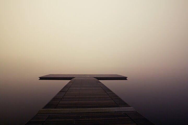 Ein Steg in Kreuzform im Nebel.